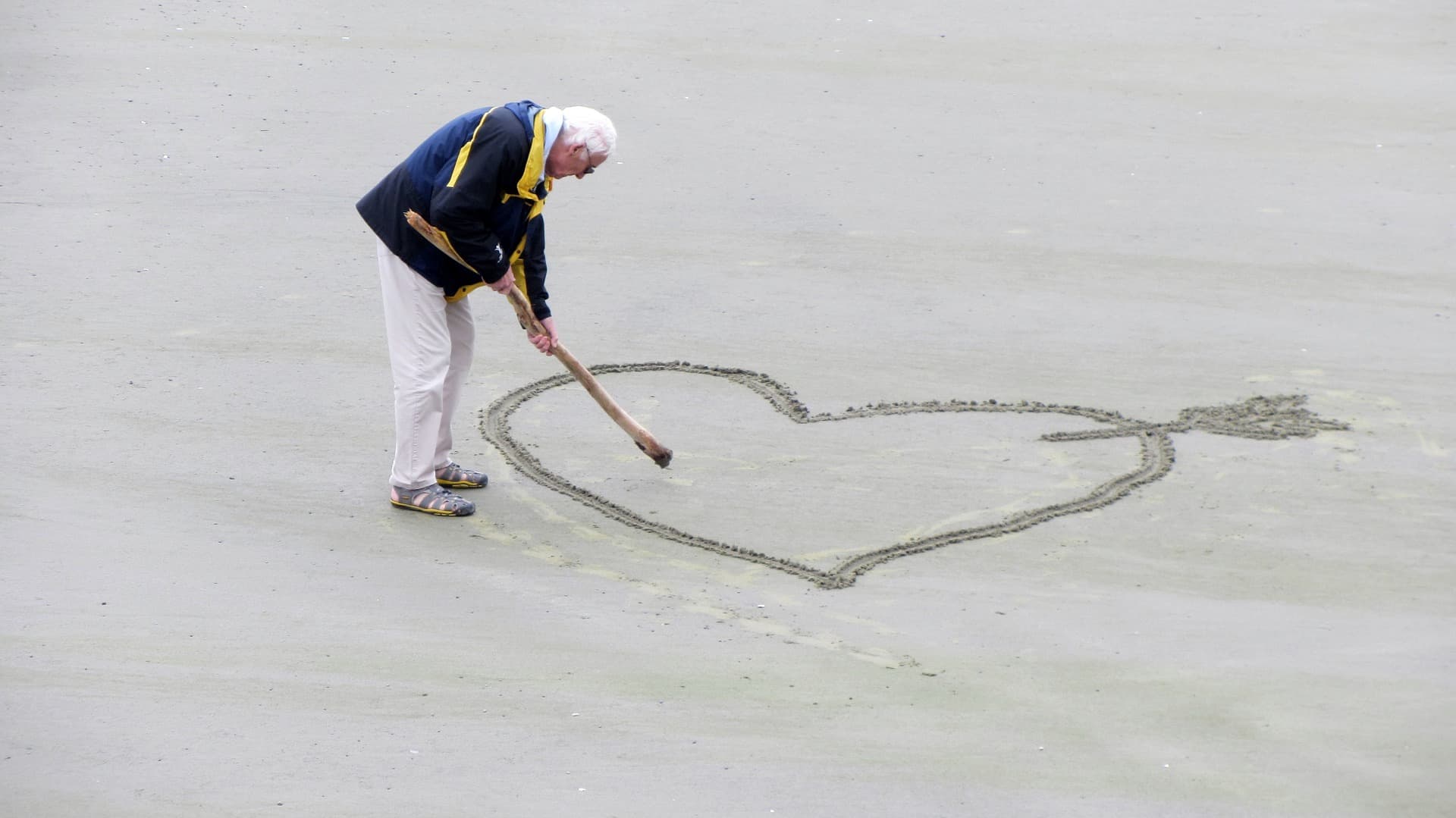 Man drawing heart in sand